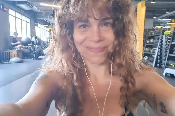 Aretha, filha de Vanusa, posa sorridente com um fone de ouvido e cabelos soltos - Metrópoles