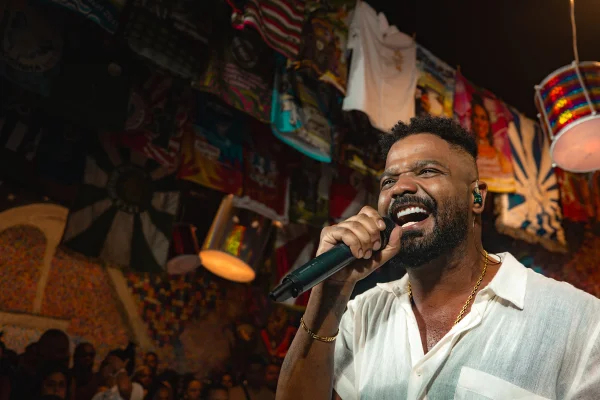 Foto colorida do cantor Arlindinho. No palco, ele canta em um microfone - Metrópoles