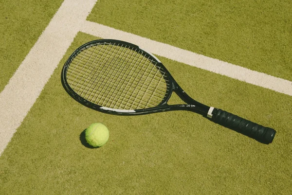 Foto de raquete e bola de tênis em quadra - Metrópoles