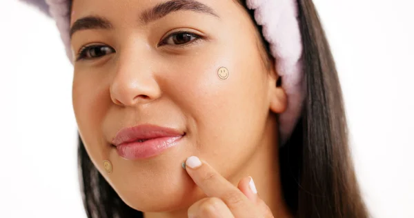 SkincarFoto colorida de menina com faixa na cabeça fazendo skincare e com adesivo para acne