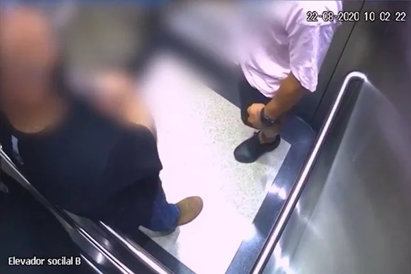 homem de blusa rosa e outro de blusa preta dentro de elevador