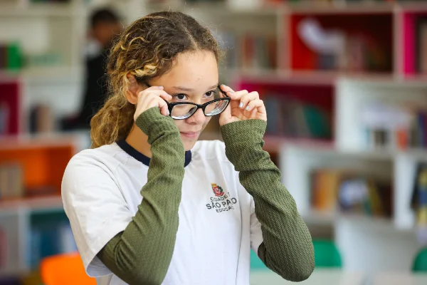 foto colorida de uma menina colocando um óculos de grau - Metrópoles