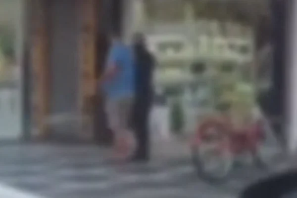 Imagem colorida de suspeito encapuzado fazendo homem refém. Metrópoles