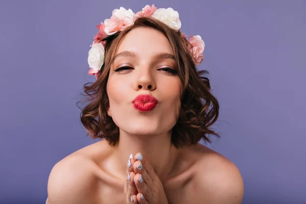 Mulher com coroa de flores mandando beijo