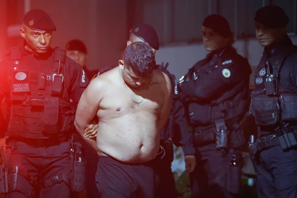 Homem sem camisa com as mãos para trás rodeado de PMs. Felype Barbosa da Silva foi preso no Entorno do DF - Metrópoles