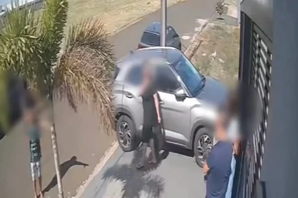 Imagem colorida, jovem escalando portão para fugir de Pit-bull - Metrópoles