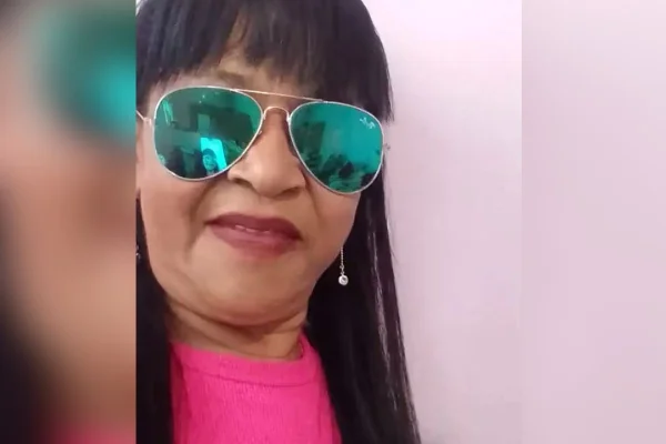 Foto colorida de mulher sorrindo e usando óculos espelhado.