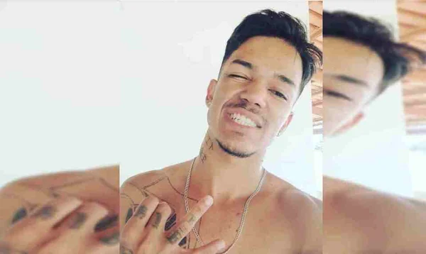 Homem sem camisa e tatuado sorrindo para foto