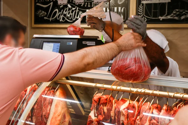 Acougueiro entrega sacola com carne bovina a cliente