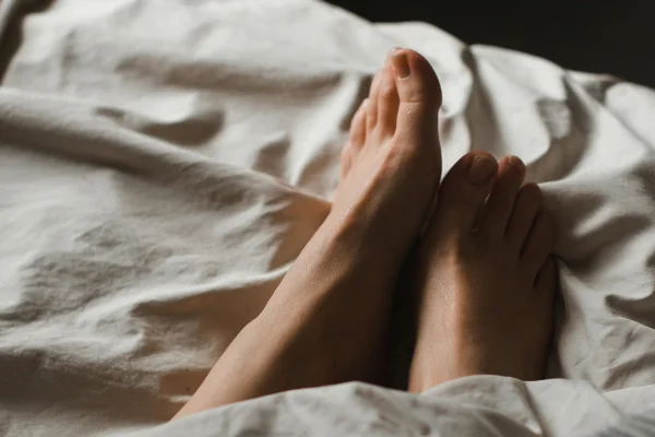 Pés de pessoa deitada em cama - Metrópoles