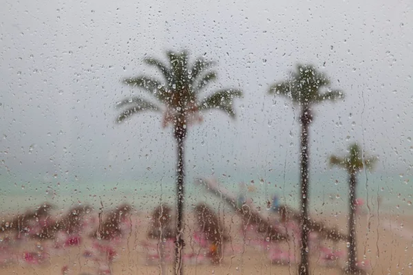 Imagem colorida: janela com chuva na praia - Metrópoles