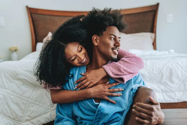 Foto colorida de um casal heterossexual negro abraçados