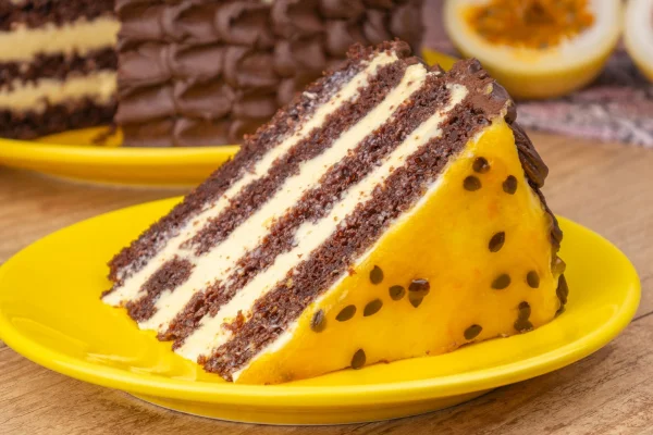 Fatia de bolo de chocolate com mousse de maracujá servida em pratos amarelo