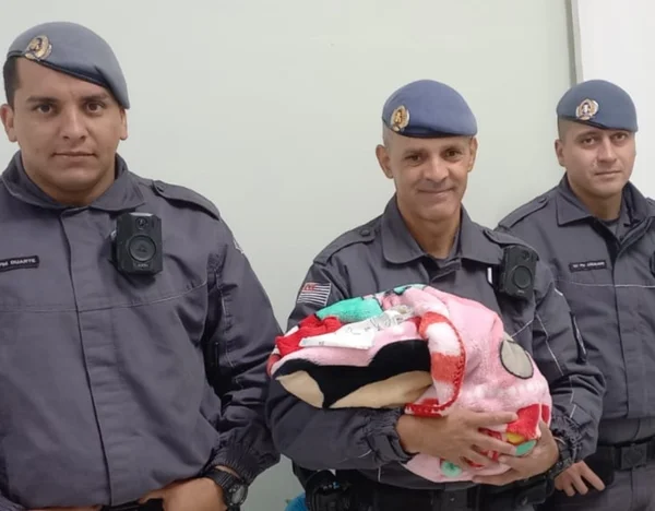 Imagem colorida de policiais militares com criança no colo