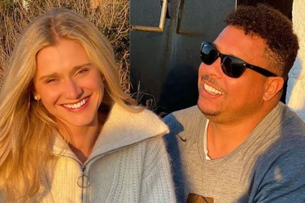 Celina Locks sorri enquanto Ronaldo Fenômeno olha para ela sorrindo