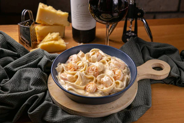 macarrão com camaroes em travessa com vinho ao fundo
