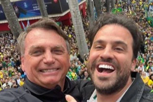 Fotografia colorida de dois homens em trio elétrico com público ao fundo