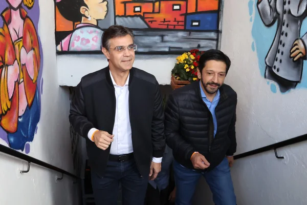 Imagem colorida mostra Rodrigo Garcia e Ricardo Nunes, ambos homens brancos de cabelo preto, subindo uma escadaria com as paredes superiores decoradas com uma pintura estilo grafite de rua