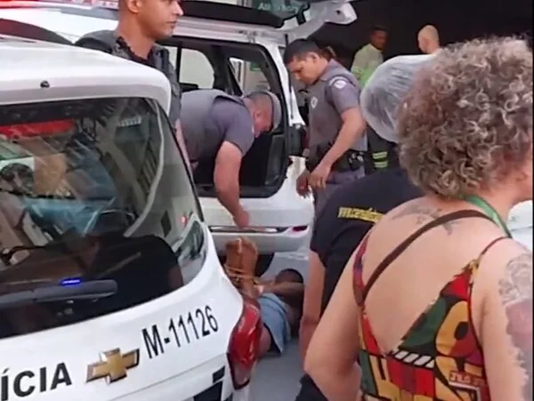 Foto colorida mostra PMs amarrando homem durante abordagem no centro de SP