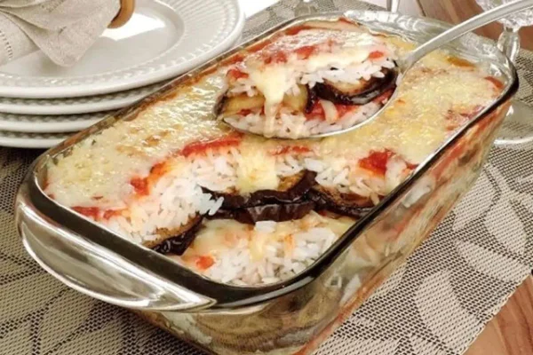 Foto colorida de um arroz de forno com berinjela à parmegiana - Metrópoles