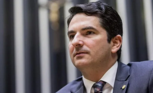 Imagem do deputado federal Gustinho Ribeiro, no plenário da Câmara. Ele veste um terno azul, uma camisa branca e usa gravata azul