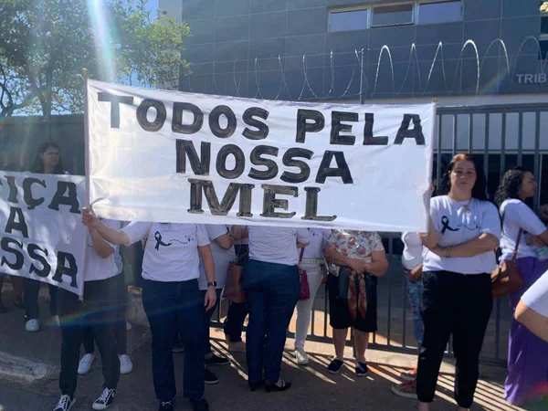 Grupo de pessoas em frente ao Tribunal do Júri de Sobradinho pedindo por Justiça. Seguram cartaz pedindo Todos pela Nossa Mel