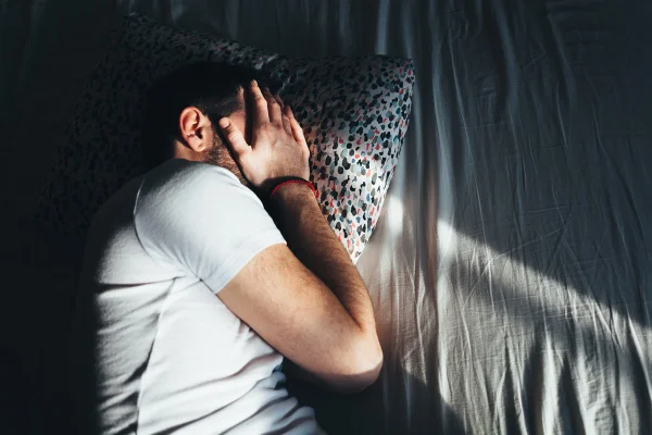 Homem deprimido deitado chorando na cama - Metrópoles