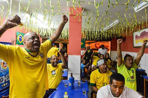 Grupo de brasileiros vestidos de verde e amarelo em uma sala decorada para torcer pelo Brasil - Metrópoles