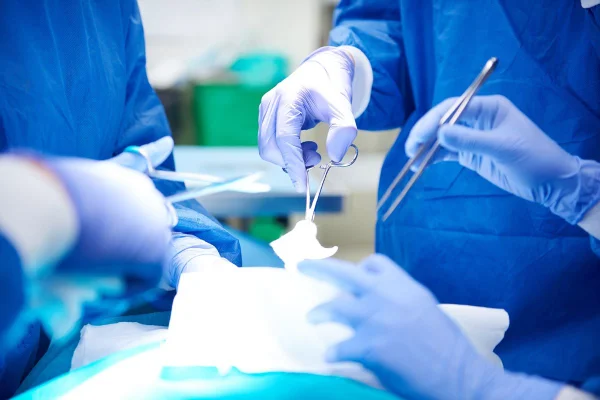 Foto colorida de mãos de médicos com luvas e equipamentos cirúrgicos - Metrópoles