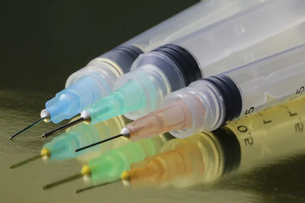 Seringas coloridas com agulhas em mesa - Metrópoles
