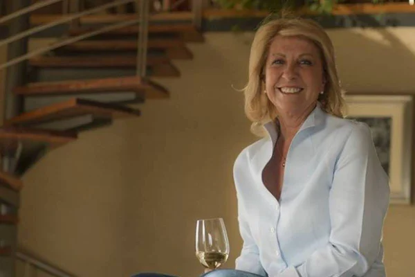 Mulher sorri com uma taça de vinho na mão
