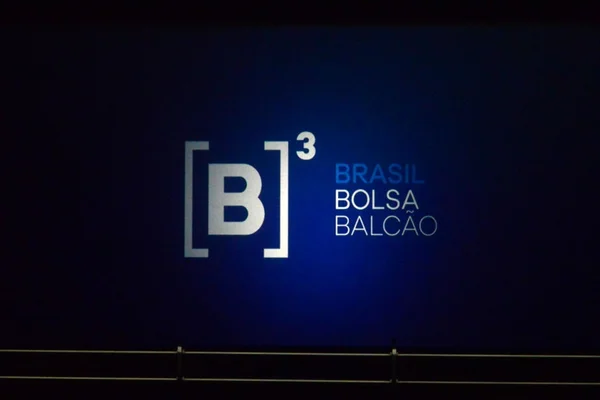 Imagem de balcão da Bolsa de Valores do Brasil, a B3, com o logtipo da B3 nas cores azul e branca, um fundo preto - Metrópoles