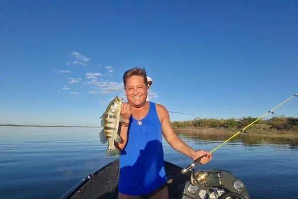 Cantor Leonardo com regata azul segunando um peixe dentro de um barco - Metrópoles