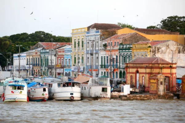 Vista panorâmica de Belém, com casas coloridas à beira do rio e pequenas embarcações ancoradas nas margens