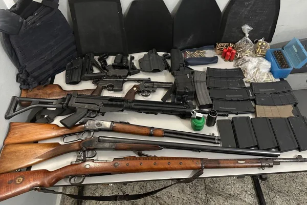 Imagem colorida mostra arsenal disposto sobre mesa. Há armas de cano longo, municões e coletes balísticos - Metrópoles