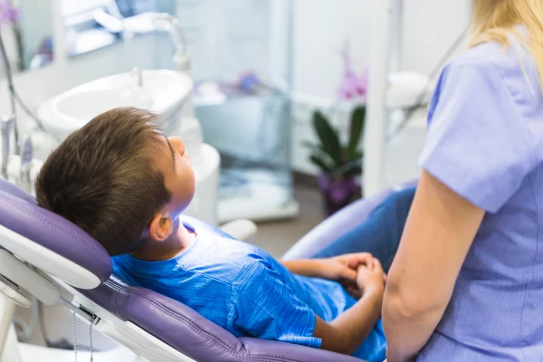 Imagem colorida de criança sendo orientada por dentista - Metrópoles