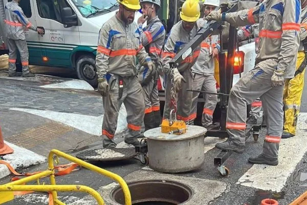 Imagem colorida mostra funcionários da Enel usando tampa de concreto na rede subterrânea de São Paulo, medida para evitar furto de cabos - Metrópoles
