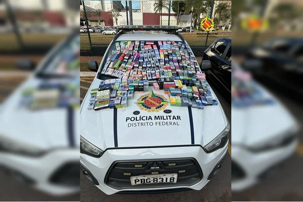 Foto colorida de carro da polícia militar do df com várias caixas de cigarros eletrônicos em cima do capô