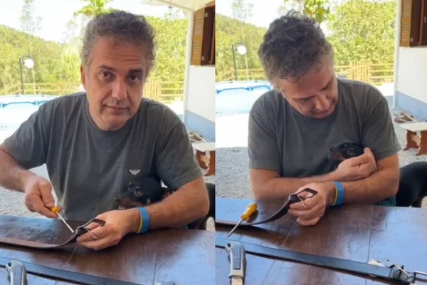 Foto colorida de um homem segurando um cachorro no colo - Metrópoles