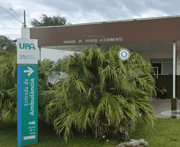Fachada de Unidade de Pronto Atendimento com placa direcionado entrada de ambulâncias e um jardim - Metrópoles