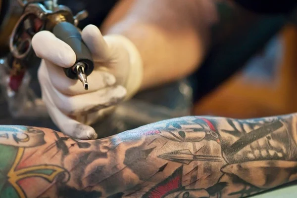 Foto colorida de mão de tatuador fazendo tatuagem - Metrópoles