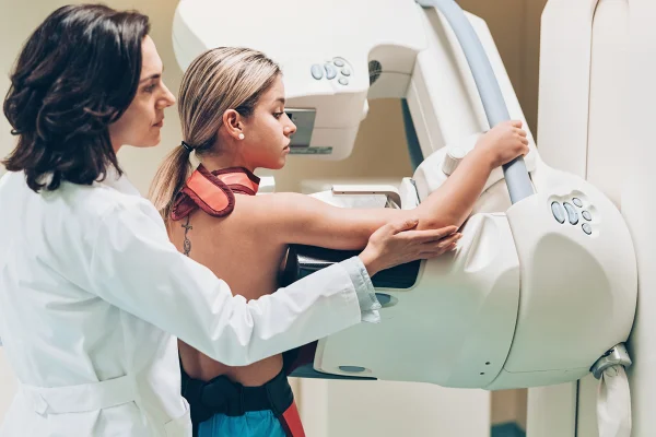 Foro colorida de uma mulher jovem realizando uma mamografia - Getty Images