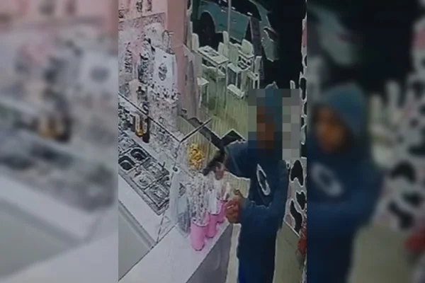 Imagem colorida de homem com casaco azul apontando arma