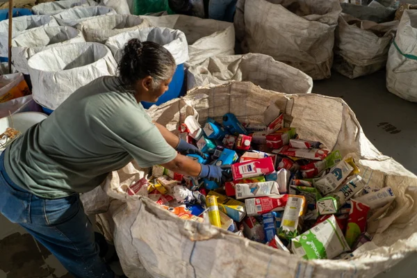 Mulher mexendo em lixo reciclável