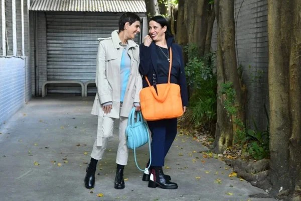 Duas mulheres se abraçando e sorrindo em calçada