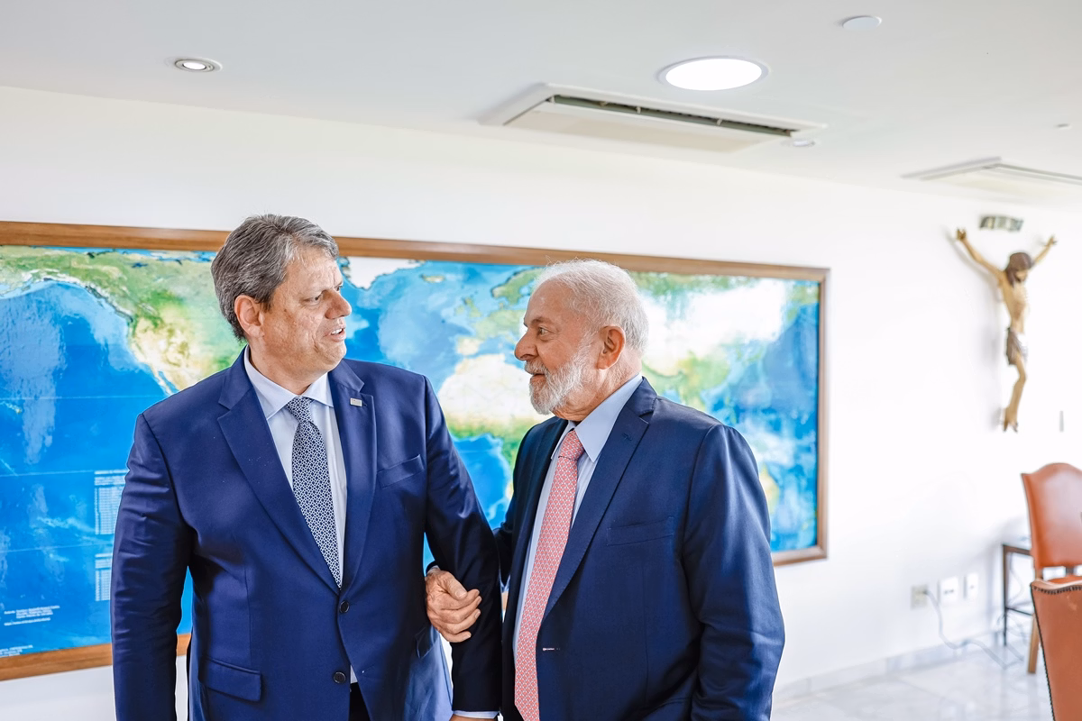 Imagem colorida mostra Lula e Tarcísio, ambos de terno azuis, de braços dados, conversando - Metrópoles