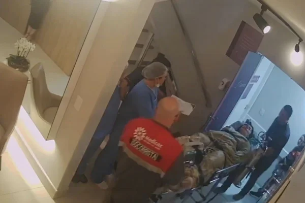 Imagem em cores de câmera de segurança mostra equipes de resgate saindo da área de procedimentos médicos.