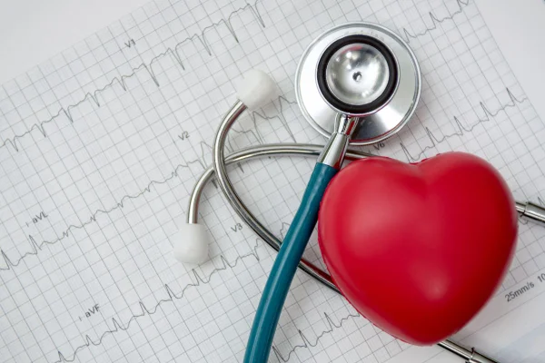 Coração vermelho em cima de um estetoscópio médico azul. Síndrome do coração partido