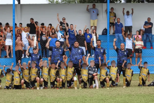 Imagem colorida de jogadores sub 11 do clube YL Esportes posando com uma mão para cima em ato contra racismo - Metrópoles