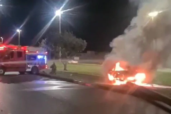 Carro pegando fogo e viatura do corpo de bombeiros ao fundo. Há muita fumaça no local - Metrópoles